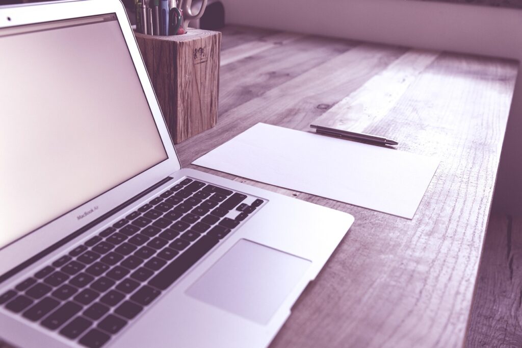 Laptop und weißes Blatt auf Tisch